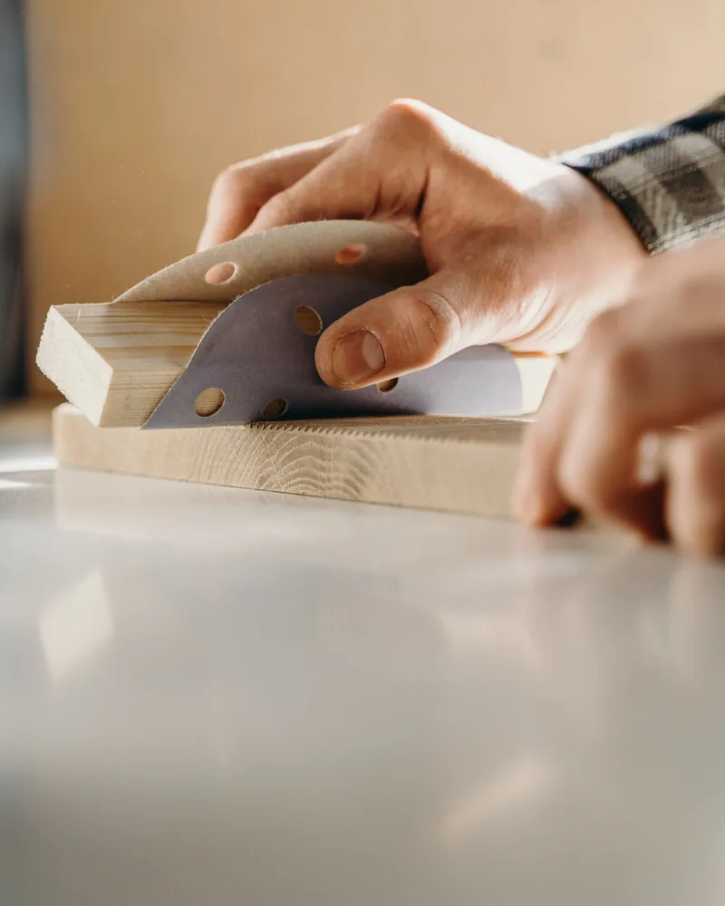 Manos lijando a mano un bloque de madera en un banco de trabajo