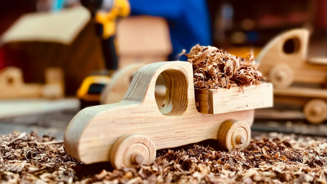 Camión de juguete de madera lleno de virutas sobre una superficie de taller
